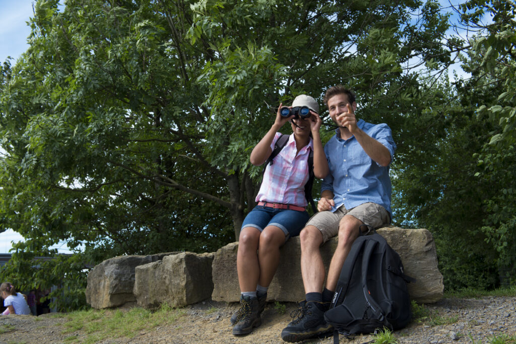 Wanderungen im Weserbergland: Zwei Wandernde mit Fernglas am Aussichtspunkt Hohenstein.